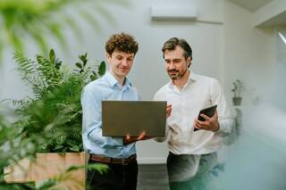 Des hommes d'affaires discutant de leur travail sur un ordinateur portable dans un bureau moderne