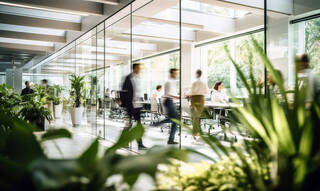 Un espace de travail lumineux où l'on voit des personnes se déplacer dans un mouvement flou au sein d'un bureau moderne