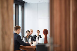 Vue d'une réunion de travail dans la salle de conférence à travers la porte ouverte, avec un espace de photocopie
